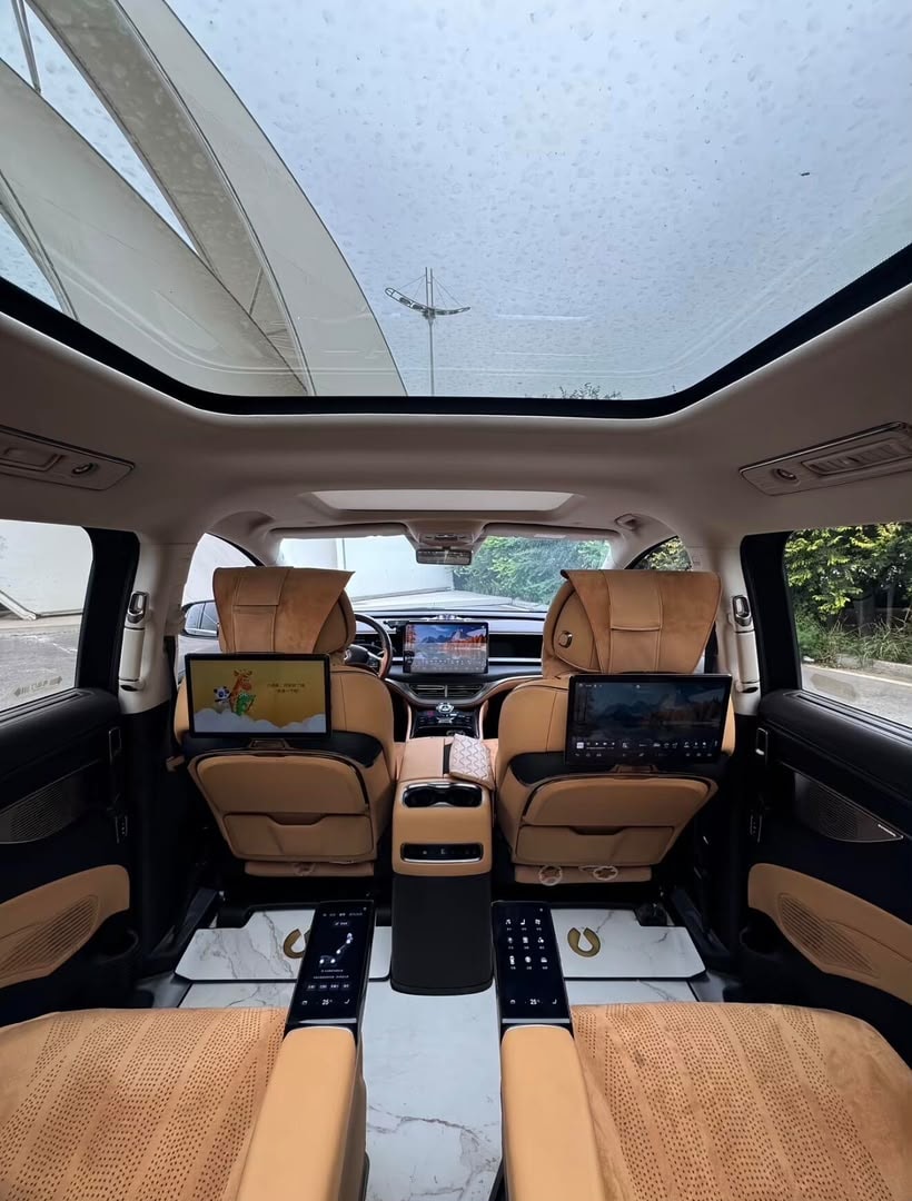 Denza D9 interior with tan captain seats, panoramic roof, and rear screens